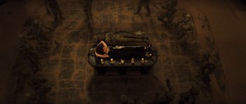 Movie still from “The Mummy” (1999), directed by Stephen Sommers – A woman laying on a bench in a dark room; Wide shot, Overhead angle