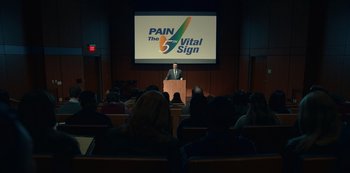 Movie still from “Dopesick” (2021), directed by Danny Strong – A man is giving a speech in front of an audience; Extreme Wide shot, Low angle