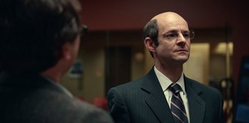 Movie still from “Dopesick” (2021), directed by Danny Strong – A man in a suit and tie looking into a mirror; Close Up shot, Over the shoulder angle