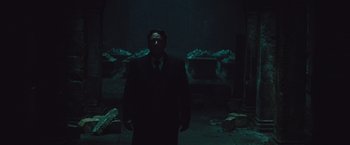 Movie still from “The Mummy” (2017), directed by Alex Kurtzman – A man in a suit standing in a dark room; Wide shot, Low angle