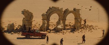 Movie still from “The Mummy” (2017), directed by Alex Kurtzman – A red pick - up truck parked in front of a stone arch; Extreme Wide shot, High angle