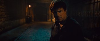 Movie still from “The Mummy” (2017), directed by Alex Kurtzman – A man standing in the dark in front of a building; Close Up shot, Over the shoulder angle