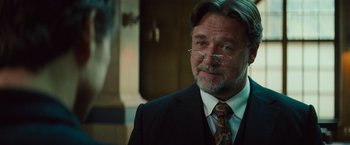 Movie still from “The Mummy” (2017), directed by Alex Kurtzman – A person wearing glasses and a suit; Close Up shot, Over the shoulder angle