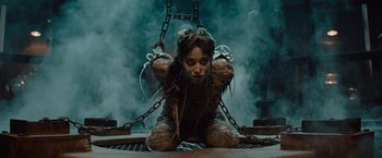 Movie still from “The Mummy” (2017), directed by Alex Kurtzman – A woman sitting on the ground wearing chains; Medium shot, Low angle