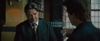 Movie still from “The Mummy” (2017), directed by Alex Kurtzman – A man wearing a suit and tie in a library; Close Up shot, Over the shoulder angle