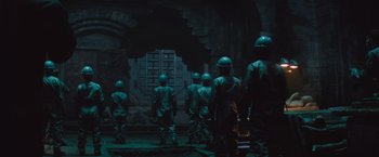 Movie still from “The Mummy” (2017), directed by Alex Kurtzman – A group of men in green uniforms standing in a dark room; Wide shot, Low angle