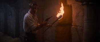 Movie still from “The Mummy Returns” (2001), directed by Stephen Sommers – A man holding a pair of guns and holding a burning stick; Medium shot, Low angle