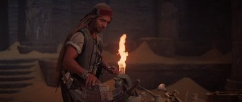 Movie still from “The Mummy Returns” (2001), directed by Stephen Sommers – A man wearing a hat is working in an outdoor workshop; Medium shot, Over the shoulder angle