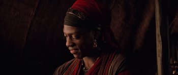 Movie still from “The Mummy Returns” (2001), directed by Stephen Sommers – A woman wearing a red headscarf and a red and black outfit; Close Up shot, Over the shoulder angle