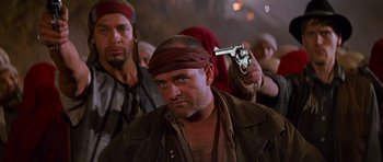 Movie still from “The Mummy Returns” (2001), directed by Stephen Sommers – A man with a bandana on his head holding a gun in his hand; Close Up shot, Over the shoulder angle