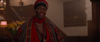 Movie still from “The Mummy Returns” (2001), directed by Stephen Sommers – A man in a red and black outfit with gold jewelry; Close Up shot, Over the shoulder angle