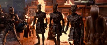 Movie still from “The Mummy Returns” (2001), directed by Stephen Sommers – A group of statues that are standing in front of a fire; Wide shot, High angle