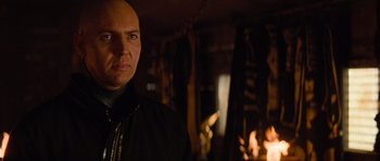 Movie still from “The Mummy Returns” (2001), directed by Stephen Sommers – A bald man in a black shirt is in front of a fireplace; Close Up shot, Over the shoulder angle