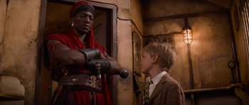 Movie still from “The Mummy Returns” (2001), directed by Stephen Sommers – A man in a red robe and a boy in a suit and tie; Medium shot, Over the shoulder angle