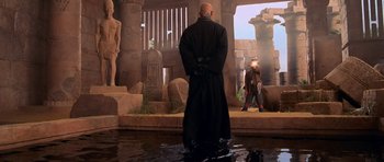 Movie still from “The Mummy Returns” (2001), directed by Stephen Sommers – A man standing in a body of water in front of an egyptian temple; Wide shot, Over the shoulder angle
