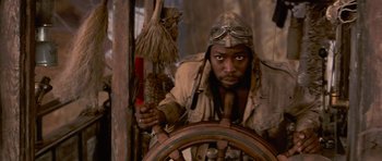 Movie still from “The Mummy Returns” (2001), directed by Stephen Sommers – A man wearing a hat and a jacket holding on to a steering wheel; Close Up shot, Low angle