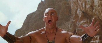 Movie still from “The Mummy Returns” (2001), directed by Stephen Sommers – A bald man with a tattoo on his arm is looking upward; Close Up shot, Low angle
