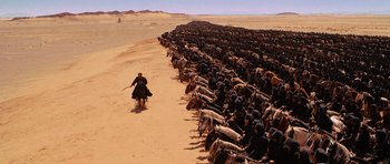 Movie still from “The Mummy Returns” (2001), directed by Stephen Sommers – A man riding a motorcycle down the middle of a herd of horses; Extreme Wide shot, High angle