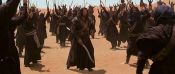Movie still from “The Mummy Returns” (2001), directed by Stephen Sommers – A group of men in black robes holding swords in the desert; Wide shot, High angle