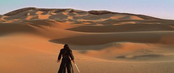 Movie still from “The Mummy Returns” (2001), directed by Stephen Sommers – A man in a black robe holding a sword in the middle of a desert; Extreme Wide shot, High angle