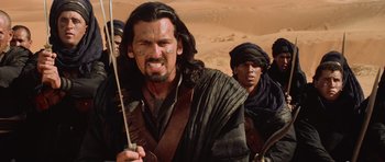 Movie still from “The Mummy Returns” (2001), directed by Stephen Sommers – A person holding a sword in a desert; Medium shot, Over the shoulder angle