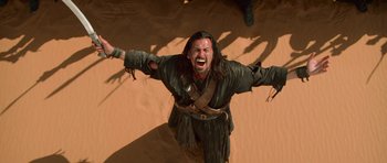 Movie still from “The Mummy Returns” (2001), directed by Stephen Sommers – A man with a beard and face paint is in the desert; Medium shot, Low angle