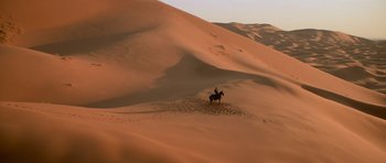Movie still from “The Mummy Returns” (2001), directed by Stephen Sommers – A man riding a horse through the sand dunes; Extreme Wide shot, High angle