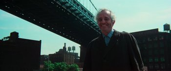 Movie still from “The New York Ripper” (1982), directed by Lucio Fulci – An older man standing in front of a bridge; Medium shot, Low angle
