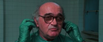 Movie still from “The New York Ripper” (1982), directed by Lucio Fulci – An older man wearing glasses and a green shirt; Close Up shot, High angle