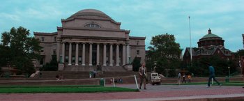 Movie still from “The New York Ripper” (1982), directed by Lucio Fulci – A man in a suit and tie walking in front of a building; Extreme Wide shot, Low angle