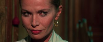 Movie still from “The New York Ripper” (1982), directed by Lucio Fulci – A person wearing a white shirt and a pair of gold earrings; Close Up shot, Over the shoulder angle