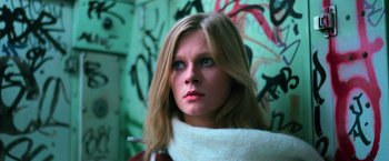 Movie still from “The New York Ripper” (1982), directed by Lucio Fulci – A young woman with long blonde hair wearing a white scarf looking at the camera; Close Up shot, Low angle