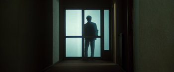 Movie still from “The New York Ripper” (1982), directed by Lucio Fulci – A man standing in front of an open glass door; Wide shot, Low angle