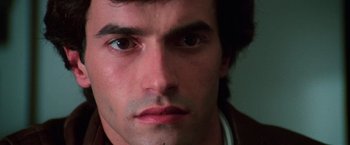 Movie still from “The New York Ripper” (1982), directed by Lucio Fulci – A man's face with a serious look on his face; Close Up shot, Low angle