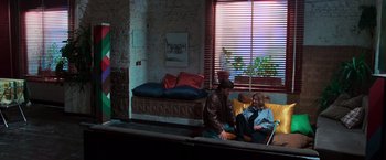Movie still from “The New York Ripper” (1982), directed by Lucio Fulci – Two people sitting on a couch in front of a window; Wide shot, High angle