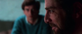 Movie still from “The New York Ripper” (1982), directed by Lucio Fulci – A man with a goatee stares into the distance; Close Up shot, Over the shoulder angle