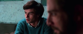 Movie still from “The New York Ripper” (1982), directed by Lucio Fulci – A man sitting in front of another man in front of a wall; Close Up shot, Over the shoulder angle