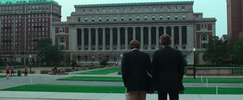 Movie still from “The New York Ripper” (1982), directed by Lucio Fulci – Two men in suits stand in front of a large building; Extreme Wide shot, Low angle