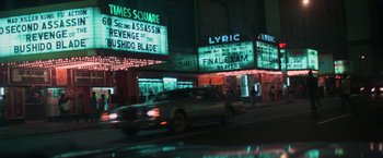 Movie still from “The New York Ripper” (1982), directed by Lucio Fulci – A car driving down a street next to a movie theater; Extreme Wide shot, High angle
