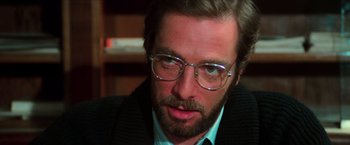 Movie still from “The New York Ripper” (1982), directed by Lucio Fulci – A person wearing glasses and a suit; Close Up shot, Over the shoulder angle