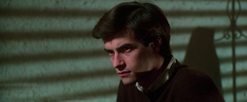 Movie still from “The New York Ripper” (1982), directed by Lucio Fulci – A young man with dark hair is looking at the camera; Close Up shot, High angle