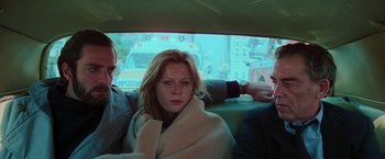 Movie still from “The New York Ripper” (1982), directed by Lucio Fulci – A woman wrapped in a blanket sitting in the back of a car; Medium shot, Low angle