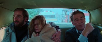 Movie still from “The New York Ripper” (1982), directed by Lucio Fulci – A woman wrapped in a blanket in the back of a car; Medium shot, Over the shoulder angle