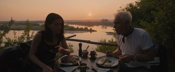 A man and a woman sitting at an outdoor table with plates of food