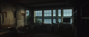 Movie still from “The Night House” (2020), directed by David Bruckner – A living room with large windows and a lake in the background; Extreme Wide shot, High angle