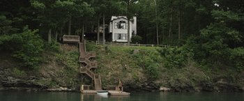 Movie still from “The Night House” (2020), directed by David Bruckner – A man standing on a dock next to a house; Extreme Wide shot, High angle