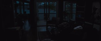Movie still from “The Night House” (2020), directed by David Bruckner – A dark room with a couch and chair in it; Extreme Wide shot, High angle
