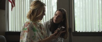 Movie still from “The Night House” (2020), directed by David Bruckner – Two women are looking at a cell phone together; Medium shot, Over the shoulder angle