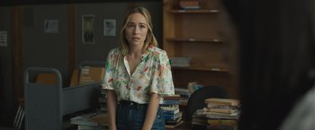 Movie still from “The Night House” (2020), directed by David Bruckner – A woman standing in front of a pile of books; Medium shot, Over the shoulder angle