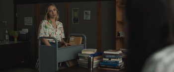 Movie still from “The Night House” (2020), directed by David Bruckner – A woman sitting at a table with a bunch of books; Medium shot, Over the shoulder angle